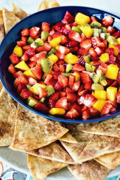 a blue bowl filled with fruit and tortilla chips on top of a plate