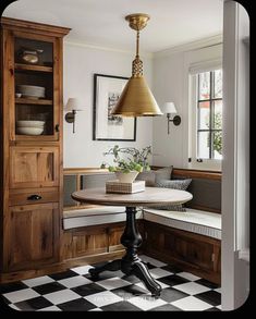 a dining room with a table, bench and cupboards in front of the window