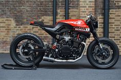 a red and black motorcycle parked in front of a brick wall