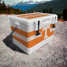 an orange and white cooler sitting on the ground