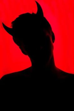 the silhouette of a man with horns on his head is shown against a red background