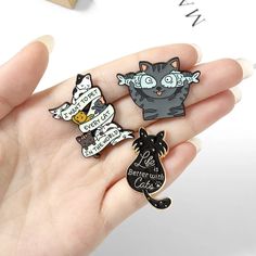 three pins in the shape of cats with sayings on them