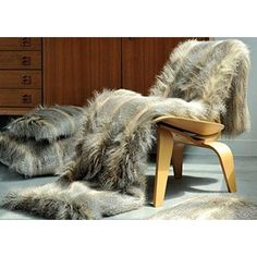 a chair with fur on it sitting in front of a dresser and chest of drawers