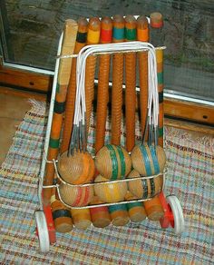 a small cart filled with lots of different colored balls on top of a rug next to a window