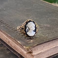 Black and white acrylic lady cameo measuring 10x14mm.On a adjustable Victorian antiqued brass cigar band style ring. Antique Cameo Ring, Antique Cameo Ring Jewelry, Luxury Vintage Cameo Ring, Victorian Gold Cameo Rings, Antique Cameo Ring Collectible, Cameo Ring, White Acrylics, Antique Rings, Antique Brass