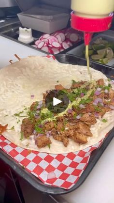 a tortilla with meat and vegetables on it is being prepared to be eaten