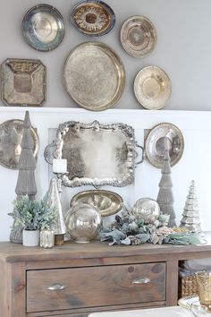 a wooden dresser topped with lots of plates and silverware next to a wall filled with christmas decorations