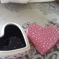 two heart shaped dishes sitting on top of a doily covered tablecloth next to each other