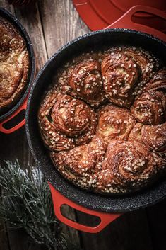 two pans filled with cinnamon rolls on top of a wooden table