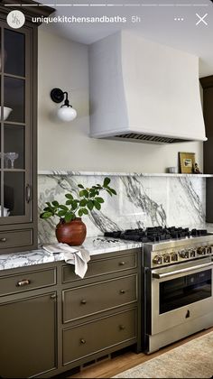 a kitchen with marble counter tops and stainless steel oven hood over the range, surrounded by cabinets