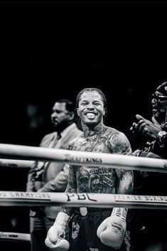 a man standing next to a boxing ring with his hands in the air and smiling