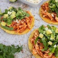 three tortillas topped with shredded chicken, avocado and cilantro