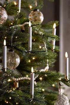 a christmas tree with lit candles and ornaments