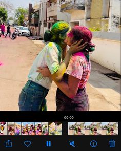 two people with colored hair are hugging each other on the street and one person has his face painted