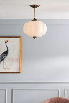 a living room scene with focus on the chair and light fixture hanging from the ceiling