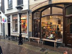 a store front with two benches in front of it on the side of a street