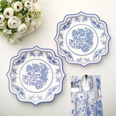 two blue and white plates sitting next to each other with silverware on top of them