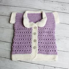 a purple and white crocheted sweater laying on top of a wooden floor