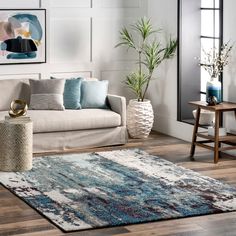 a living room filled with furniture and a rug on top of a hard wood floor