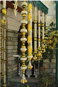 yellow and white flowers are hanging from the side of a building in front of a doorway