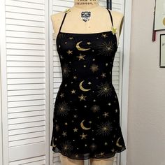 Stretchy Mesh Dress Is Fully Lined. It Has An Open Strappy Back That Is Adjustable. The Front Of The Straps Have 2 Cute Embroidered Stars That Are Sewn On. The Print Has Gold Glitter And Printing. Includes A Headband Of Glittery Gold Stars. Total Length Is About 30". Star Dress Short, Stars Dress, Embroidered Stars, Star Dress, Mesh Dress, Gold Stars, Dolls Kill, Doll Dress, Gold Glitter