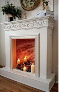 a white fireplace with lit candles in front of it and a clock on the wall