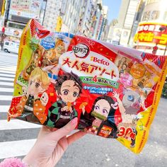 a person holding up a bag of food in front of a street with buildings and cars