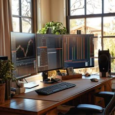 two computer monitors sitting on top of a wooden desk