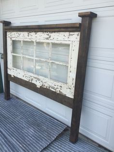 an old window frame sitting on the side of a garage door next to a rug