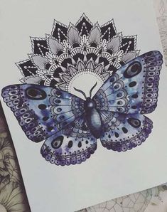 a blue butterfly with intricate designs on it's wings is sitting on top of a piece of paper