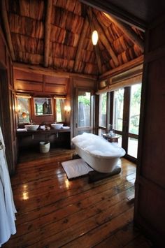 a bathroom with wood flooring and a large bathtub in the middle of it