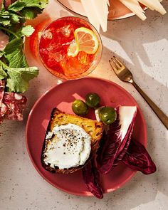 a red plate topped with food next to a bowl of salad and a glass of wine