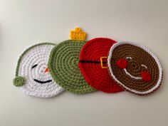 three crocheted coasters with faces on them