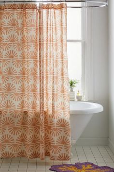 an orange and white shower curtain in front of a bathtub with a purple rug on the floor