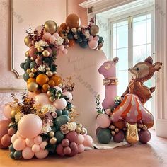 an elaborate balloon arch is decorated with balloons and other decorations for the entrance to a room