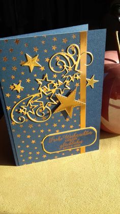 a blue and gold greeting card with stars on the front, sitting on a table