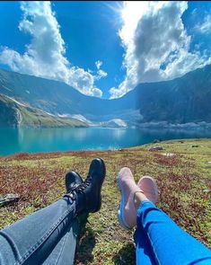 two people are sitting on the grass with their feet up