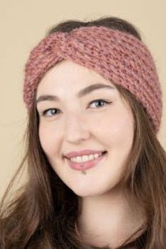 a woman with long hair wearing a pink headband smiles at the camera while standing in front of a beige background