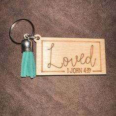 a wooden keychain with the word loved on it and tassels attached