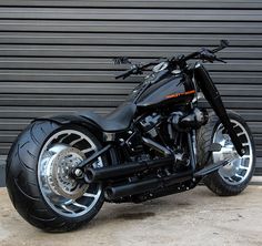 a black motorcycle is parked in front of a garage door and has chrome rims