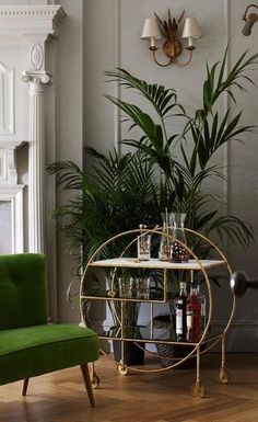 a green chair sitting next to a table with bottles on it and a potted plant