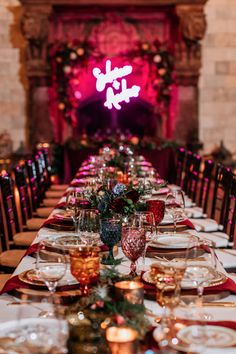 a long table is set up with place settings and wine glasses on it for an elegant christmas dinner