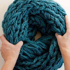 someone is holding up a blue yarn ball with their hands on the top and bottom