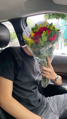 a man sitting in the back seat of a car holding onto a bunch of flowers