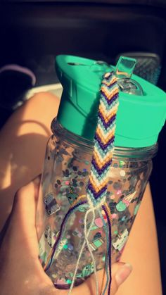 a person holding a glass jar with a colorful tie on it's handle and lid