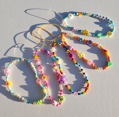 four bracelets with beads and charms on white table top next to string of hair clip