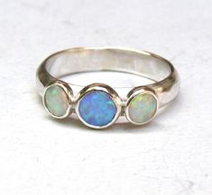 OPAL RING You are looking at a beautiful HAND MADE silver ring with opal stones. The stones are setting in silver bazel. It is impressive, powerful and very beautiful ring. Made to order any size This ring can be made to order in any size. Please note your desired size in the message to seller area at checkout. sizewhite opal stone is 5 mm. size big blue opal is 6mm width ring:4mm Come in a gift box. Fallow me on facebook for newest updates. http://www.facebook.com/pages/Orit-Naar-jewelry/174677 Opal Jewellery, Mothers Day Rings, Lotus Ring, Blue Opal Ring, Turquoise Jewelry Native American, Hand Ring, Engagement Ring Sizes, Silver Engagement Rings, Fabulous Jewelry