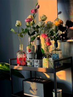 flowers and liquor bottles on a shelf in front of a mirror