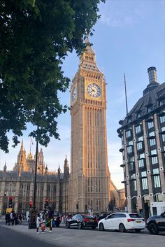 the big ben clock tower towering over the city of london, england with cars parked in front