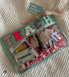 a teal tin with letters and magnets in it sitting on a white blanket